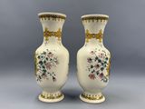deux vases blancs ornés de motifs floraux, posés sur une surface grise
