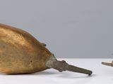 a golden object sitting on a table next to an apple