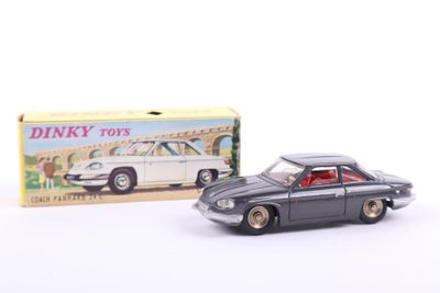 toy car in front of a box of dinky toys on a white surface