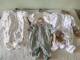 several baby clothes are laid out on a bed in a row