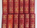 six livres rouges sont empilés les uns sur les autres sur une table