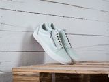 des Vans Old Skool blanches posées sur une caisse en bois