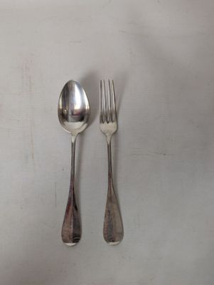 two spoons and a fork on a white table