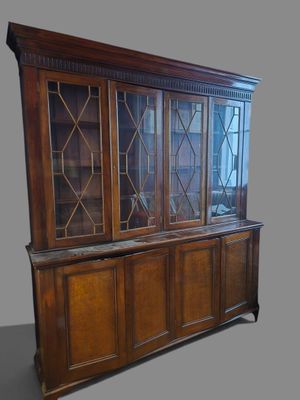 an old wooden china cabinet with glass doors on top of it