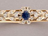 a close up of a gold bracelet with a sapphire and diamonds