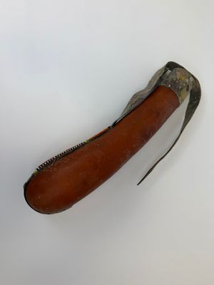 un vieux couteau avec un manche en cuir posé sur une surface blanche