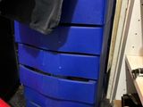 une commode bleue dans une pièce où se trouve une chaise rouge
