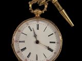 une montre de poche en or et un stylo sur fond noir