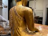 a statue of a person sitting on a table next to a statue of a person