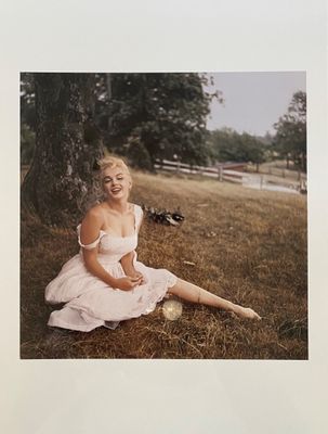 photograph of a woman in a white dress sitting in the grass