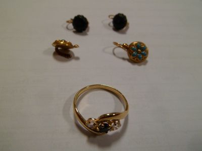 trois bagues et deux boucles d'oreilles posées sur une surface blanche
