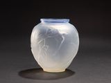 un vase blanc avec un couvercle bleu posé sur une surface noire