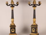 pair of black and gold candelabs with candles on pedestals
