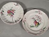 two plates with flowers and birds on them sitting on a table