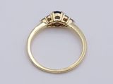 a close up of a gold ring with a sapphire and three diamonds