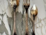 three silver spoons and two silver spoons on a marble table