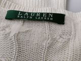 the label of a white sweater with a green ribbon on it
