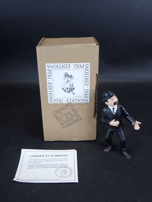 une petite figurine représentant un homme en smoking, à côté d'une boîte
