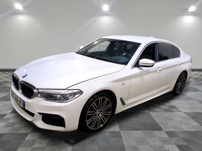 La berline BMW blanche est garée sur un sol en carrelage à damier.
