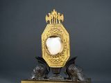 a gold clock with a white ball in the middle of it