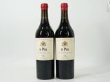 two bottles of red wine sitting next to each other on a white surface