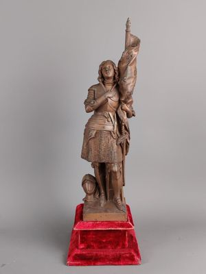 une vieille statue en bronze représentant un homme tenant une épée, posée sur un socle rouge