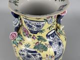a yellow vase with blue and pink flowers on it