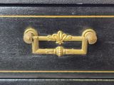 a black and gold chest of drawers with a gold handle
