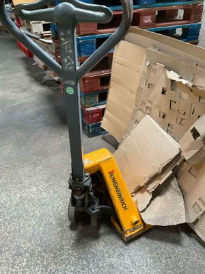 une pile de cartons posée par terre à côté d'un chariot élévateur