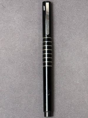 un gros plan d'un stylo posé sur une table, sur fond gris