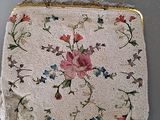 a white purse with flowers on it on a table