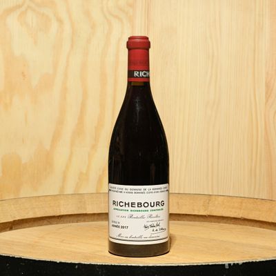 a bottle of wine sitting on top of a barrel