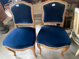 une paire de fauteuils en velours bleu, avec des bordures dorées et des pieds en bois