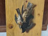 a painting of a dead bird hanging on a wall