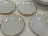 four white plates with gold rims and a bowl on a table