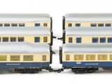 two blue and white train cars sitting next to each other on a white surface
