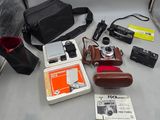 un appareil photo, un étui pour appareil photo, un appareil photo et d'autres objets posés sur une table