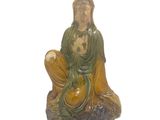 une statue représentant une femme assise sur un rocher