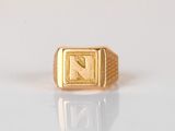 an image of a gold signet ring with an arrow symbol on it