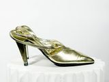 un gros plan sur une paire de chaussures dorées posées sur un socle blanc