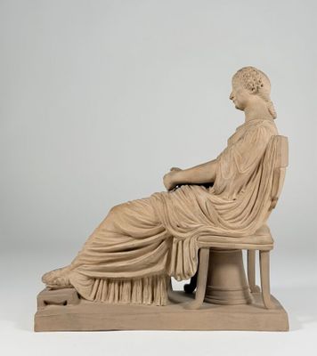 a statue of a woman sitting on a bench with her legs crossed