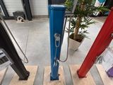 une pompe à main bleue et rouge posée sur un plancher en bois