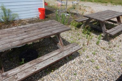 deux tables de pique-nique et une poubelle devant une maison bleue