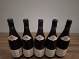 six bottles of wine are lined up on a wooden table