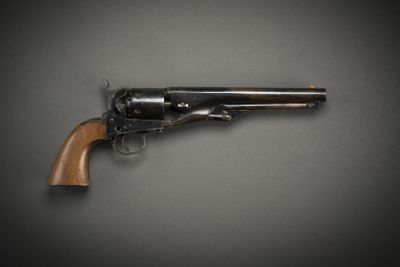 an old revolver with a wooden handle on a gray background