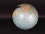 a small globe that is on a stand on a black surface