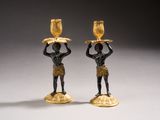 pair of black and gold candlesticks with a man holding a bowl on his head