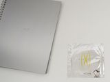 a silver notebook with a smiley face on it next to a packet of condoms