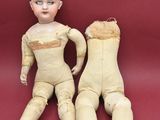 pair of old wooden dolls sitting next to each other on a red surface