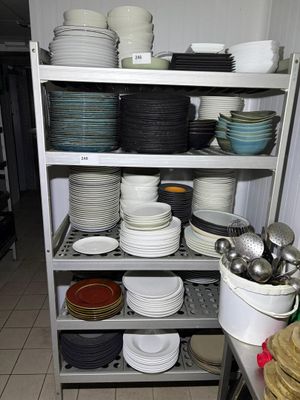 many plates and pans stacked on a shelf in a kitchen